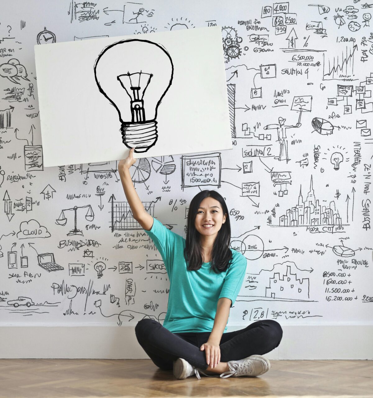 Asian woman holding a white board with a light bulb drawn on it.